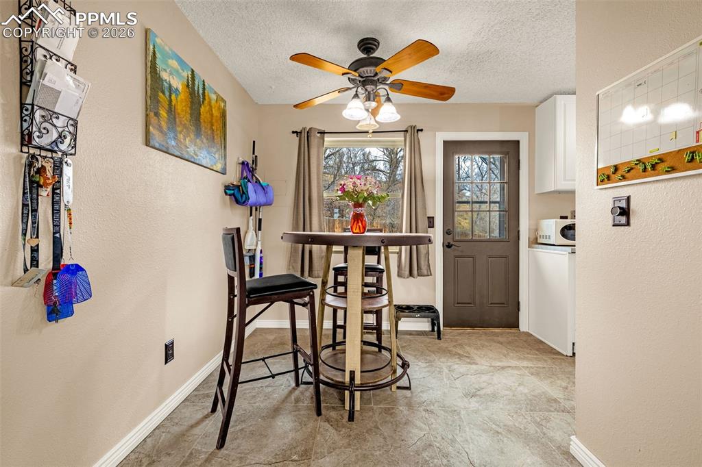 Dining area featuring a textured wall, a ceiling fan, and a textured ceiling