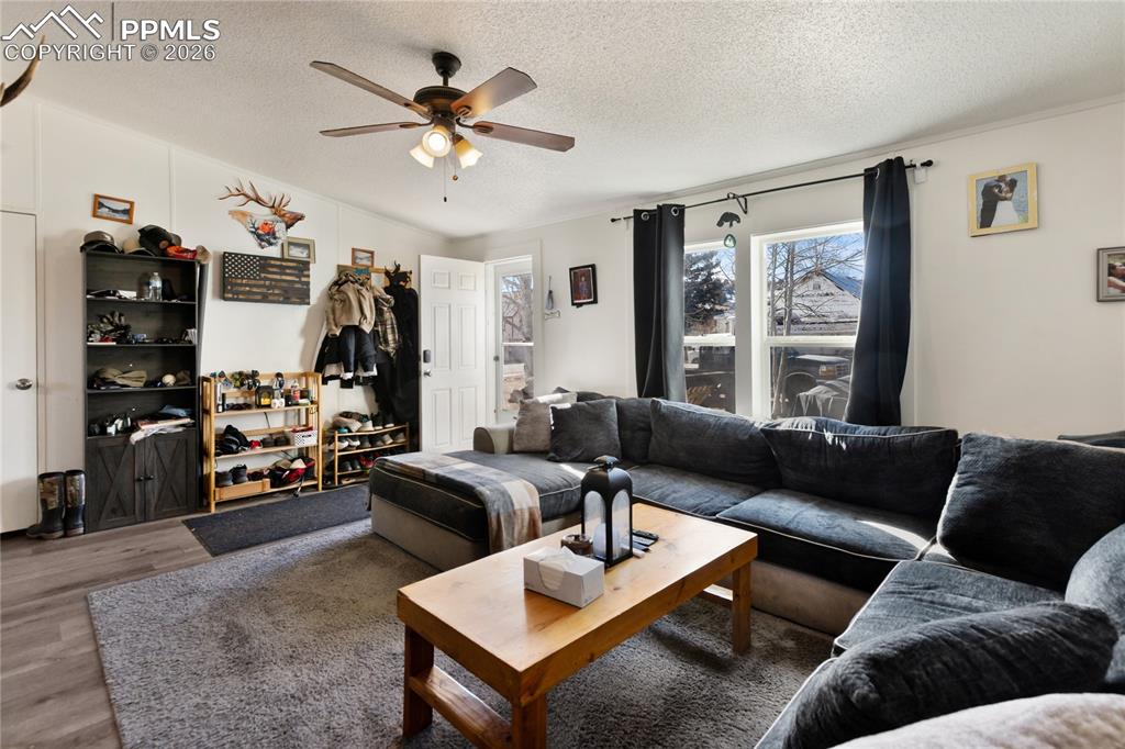 The living area featuring wood finished floors, a textured ceiling, and a ceiling fan!