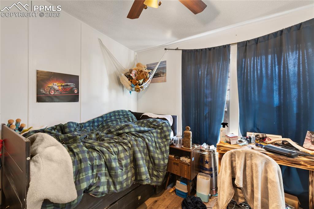 A bedroom with wood floors and a ceiling fan!
