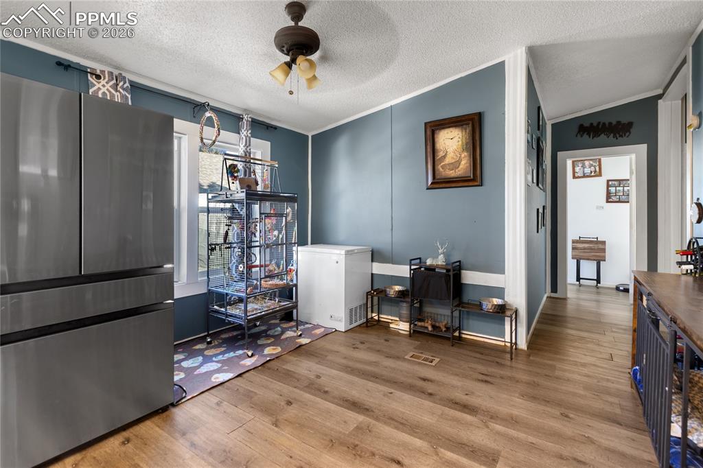 The dining space with wood floors, ceiling fan, and ornamental molding!