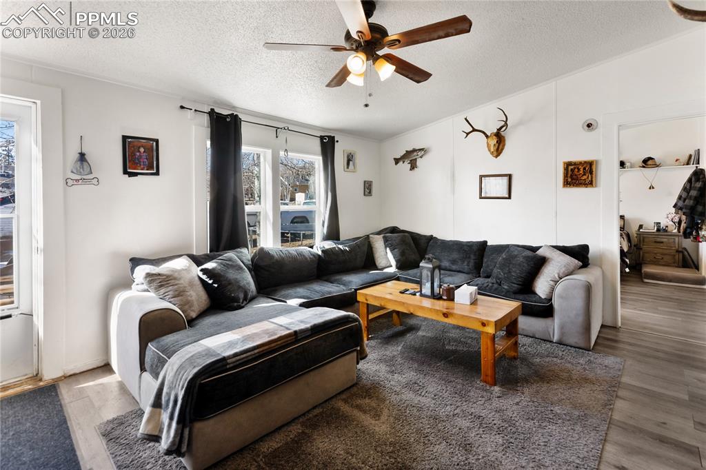 The living area featuring wood finished floors, a ceiling fan!