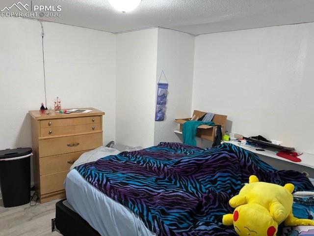 Bedroom with a textured ceiling and wood finished floors