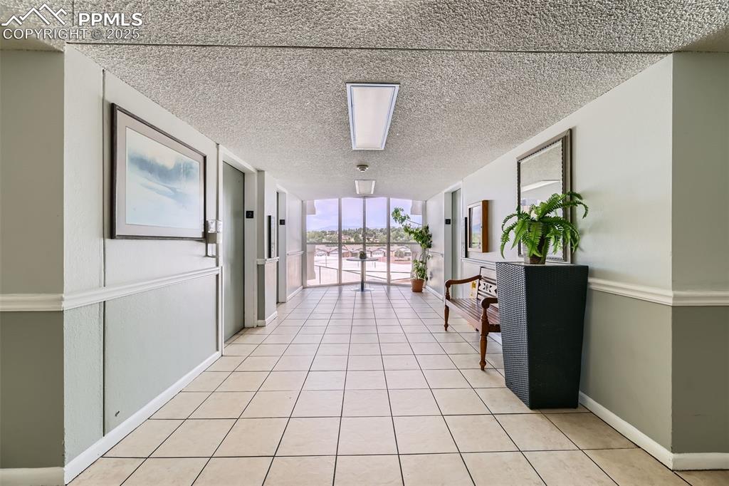 Hall featuring a textured ceiling and light tile patterned flooring