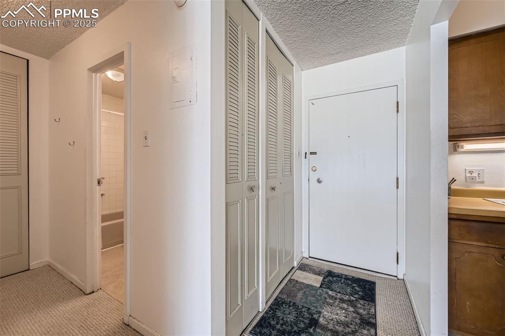 Hall with a textured ceiling and light colored carpet