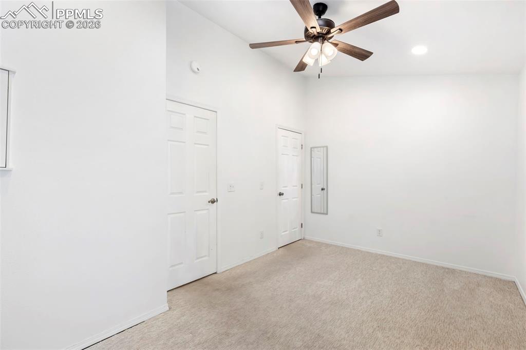 Bedroom featuring a high ceiling, light colored carpet, a ceiling fan, and recessed lighting