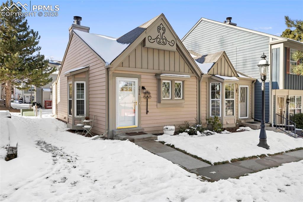 View of front facade featuring board and batten siding, a chimney, and entry steps