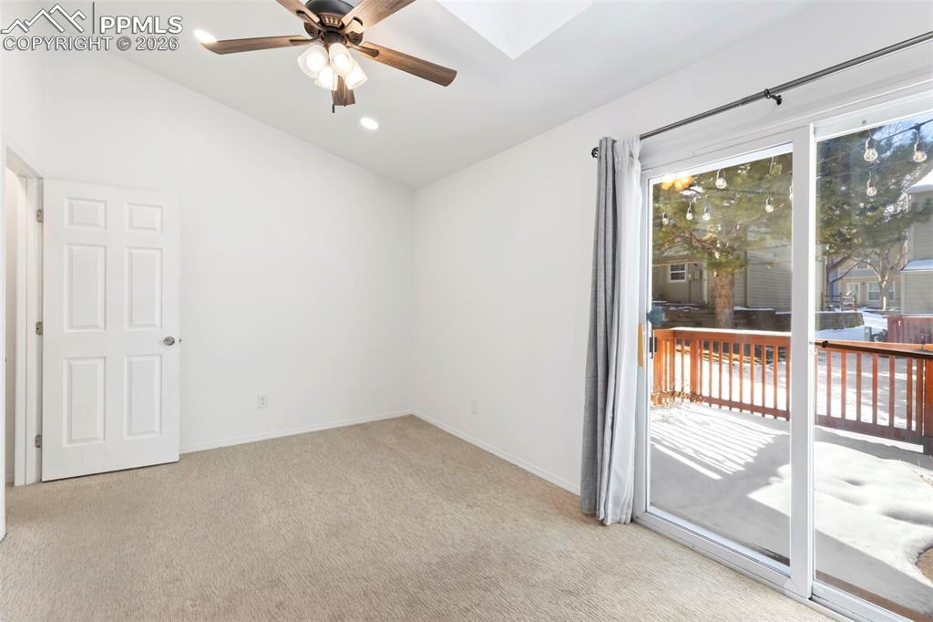Bedroom with vaulted ceiling, a skylight, ceiling fan, and light carpet