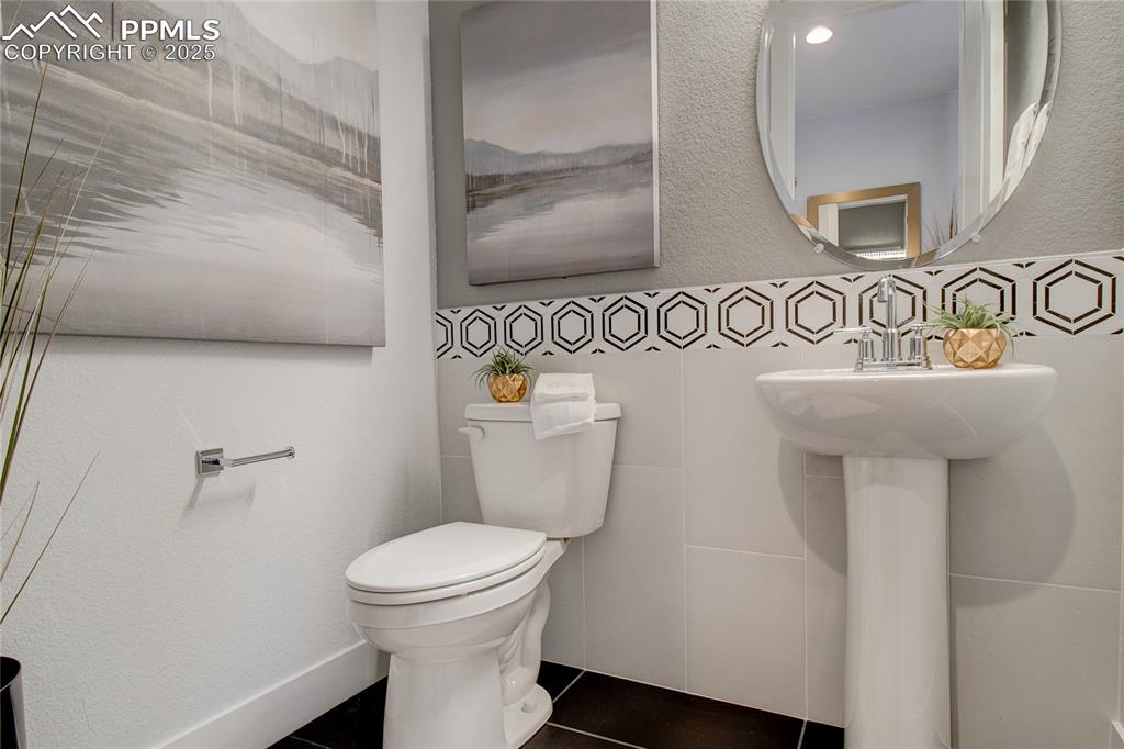 Half bathroom featuring a textured wall and dark tile patterned floors