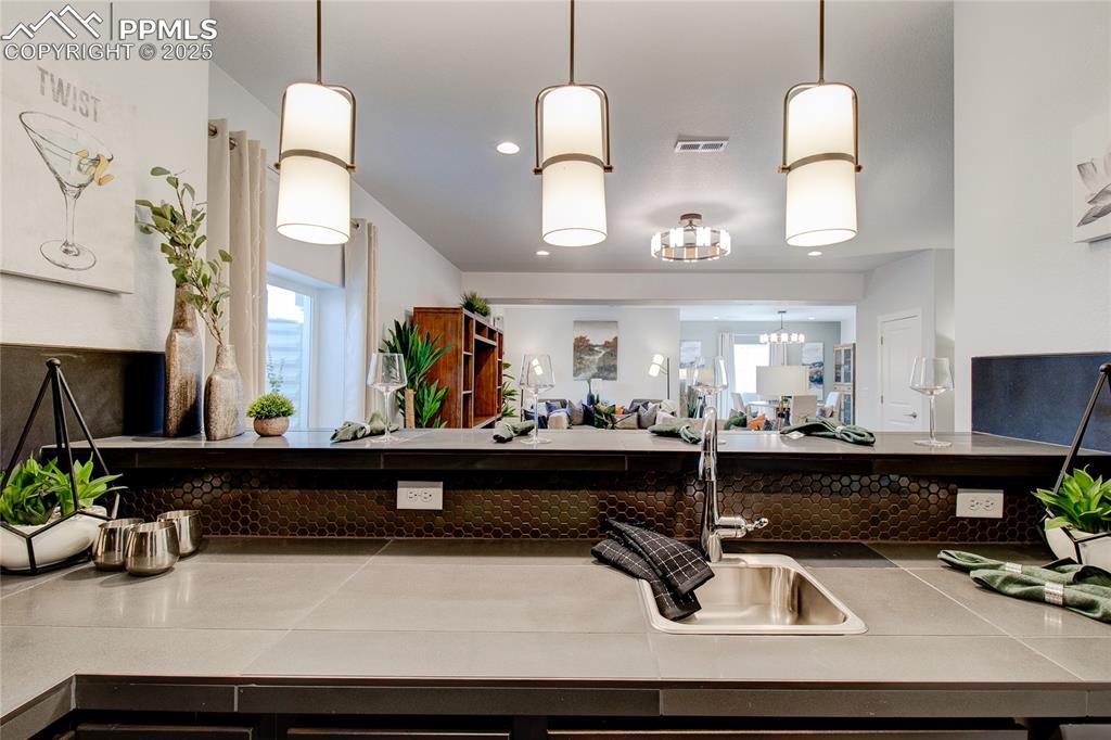 Kitchen with tile countertops, hanging light fixtures, healthy amount of natural light, and a chandelier