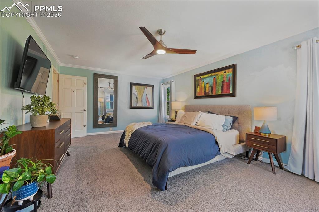 Bedroom with light carpet, ceiling fan, and ornamental molding