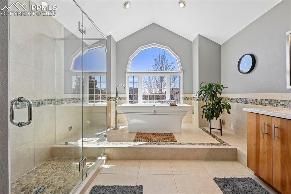 Bathroom featuring tile walls, light tile patterned floors, a shower stall, a freestanding bath, and vanity