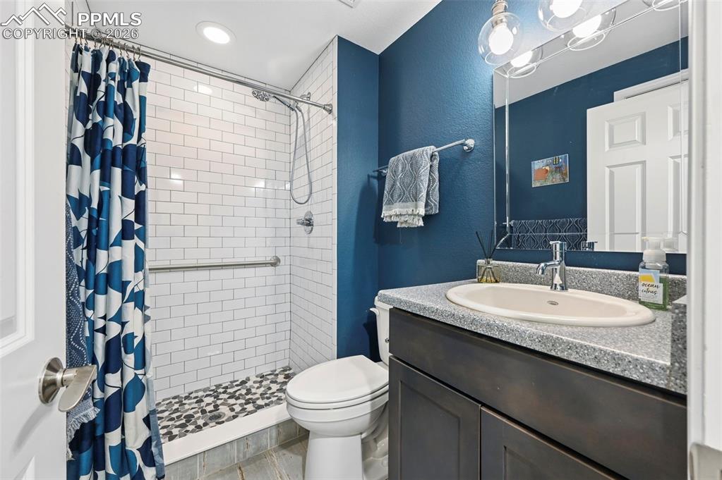 Bathroom with vanity, a stall shower, a textured wall, and recessed lighting
