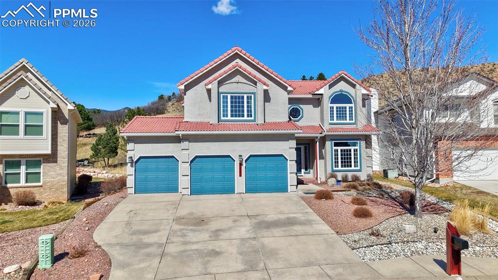 View of front of property featuring driveway, a tile roof, stucco siding, and an attached garage
