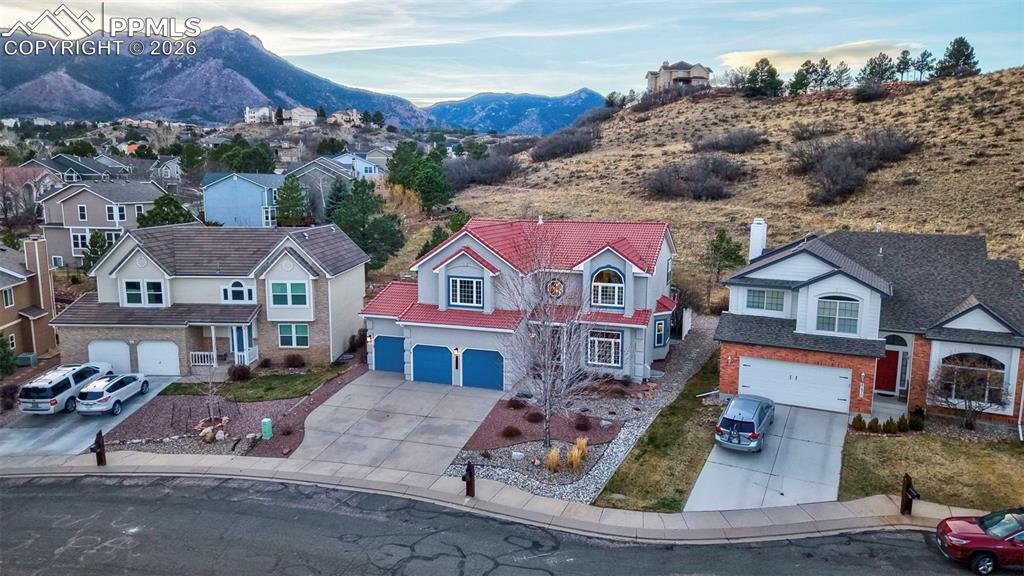 View of front of home featuring driveway, a residential view, an attached garage, and a mountain view