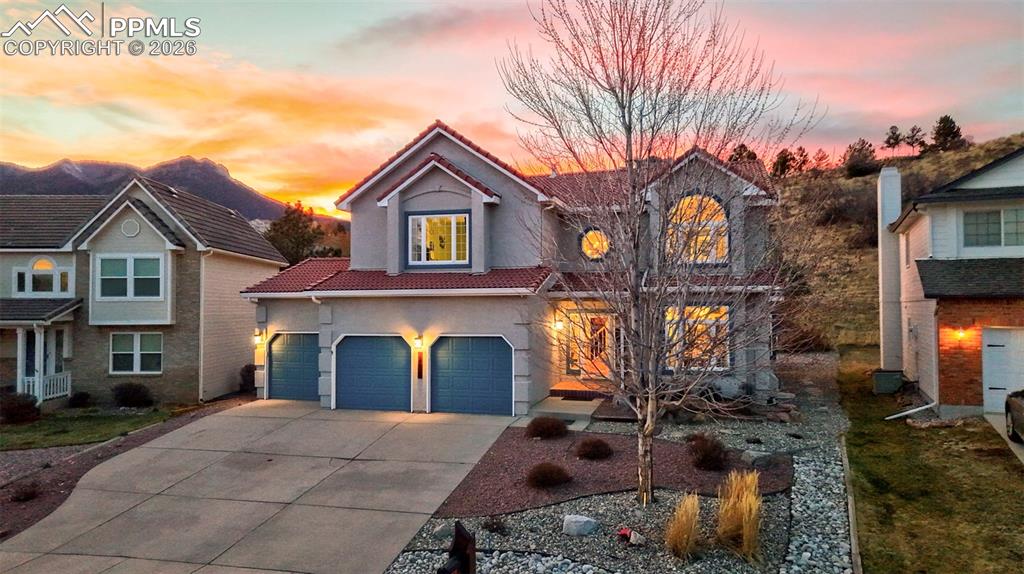 View of front of house featuring a tile roof, driveway, stucco siding, and a garage