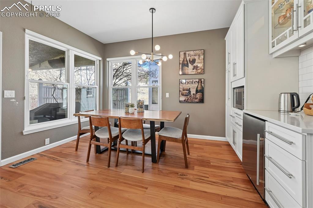 Dining area with a chandelier, wood finished floors, and beverage cooler