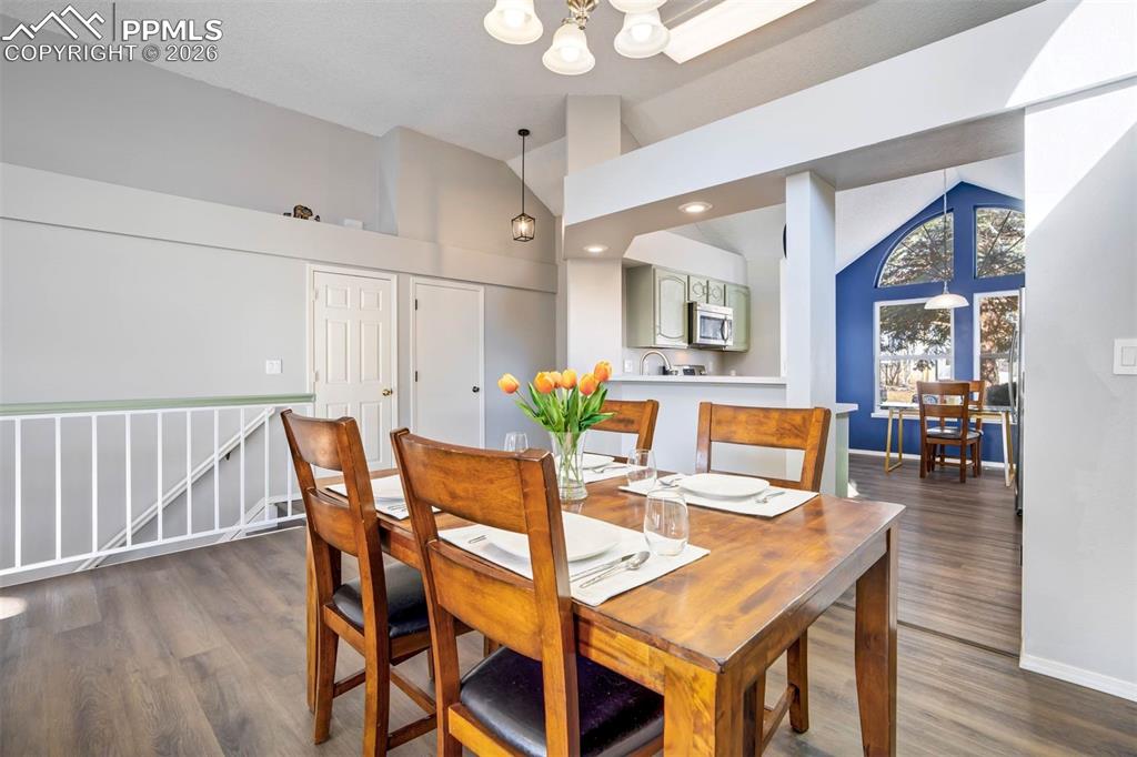 Dining space with lofted ceiling, dark wood finished floors, and a chandelier