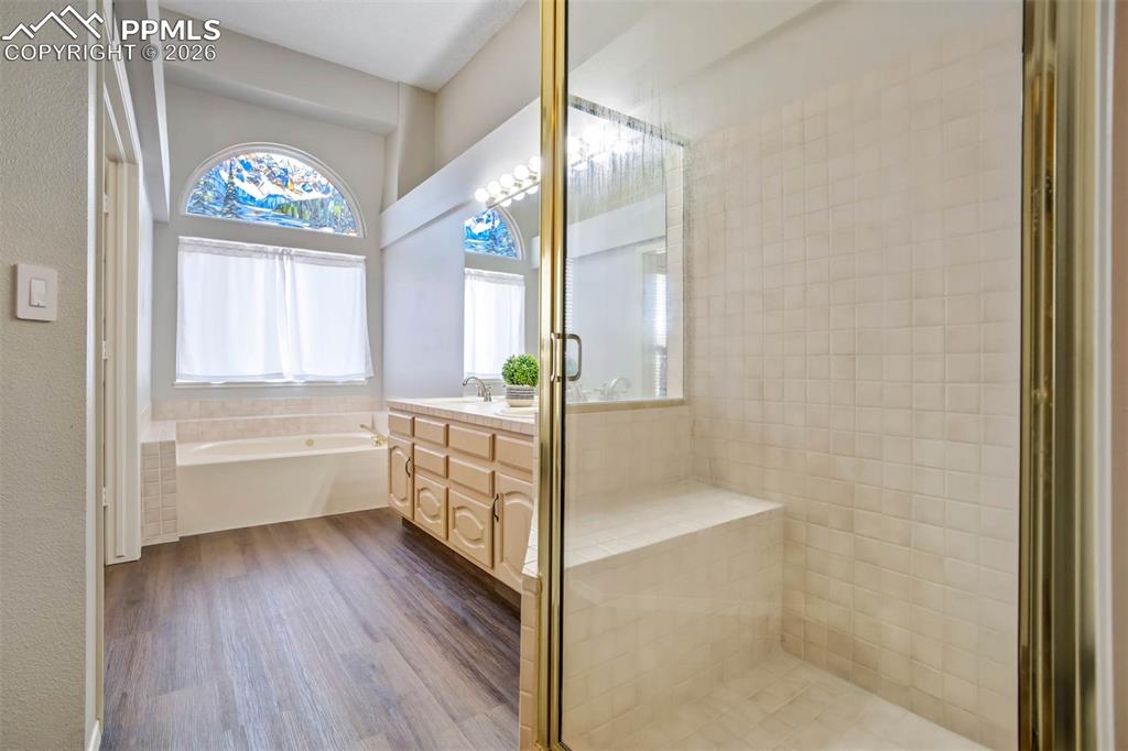Full bath featuring double vanity, a shower stall, and jet tub