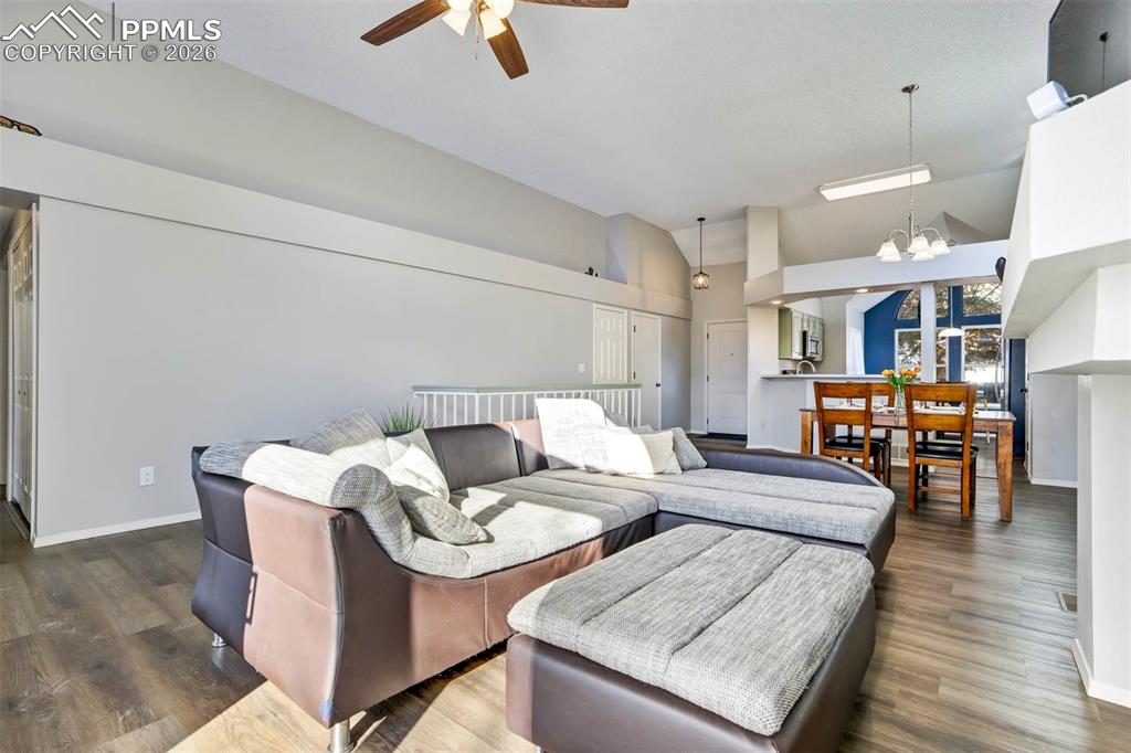 Living area with suspended lighting, wood finished floors, a ceiling fan, and vaulted ceiling