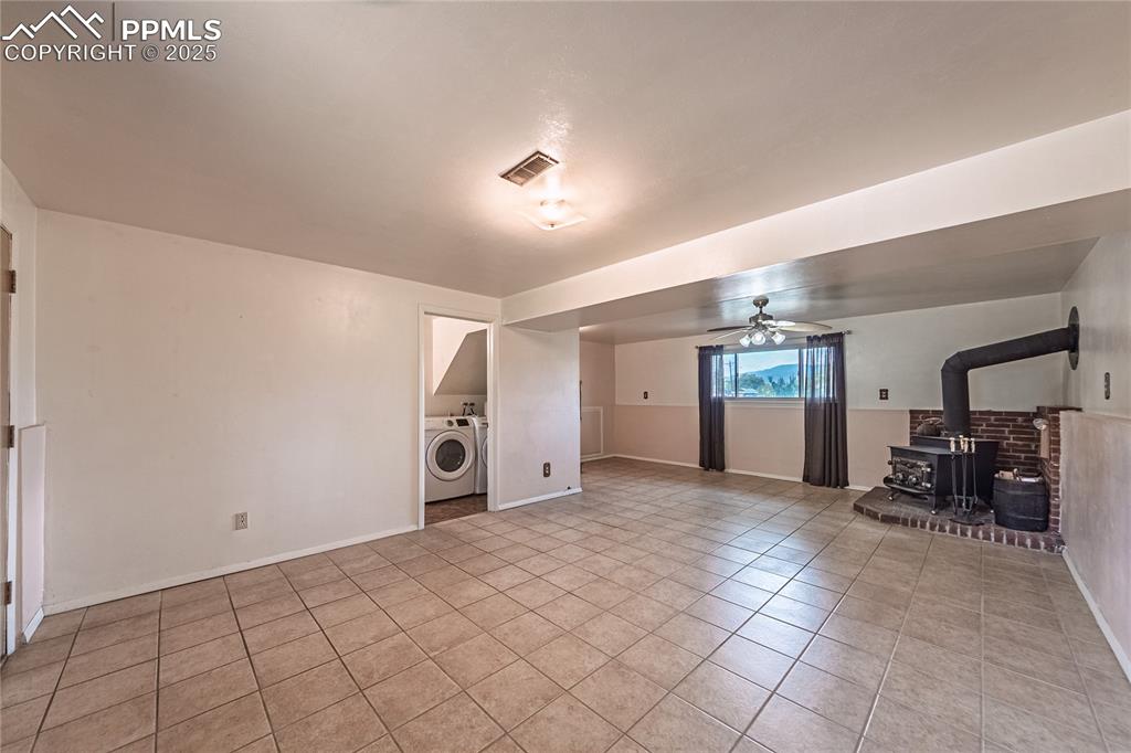 ceiling fan, a wood stove, and light tile patterned flooring