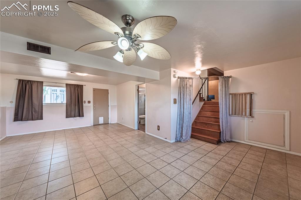 living room with light tile patterned floors, stairway, and a ceiling fan