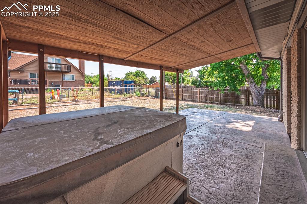 Fenced backyard with a patio and a hot tub