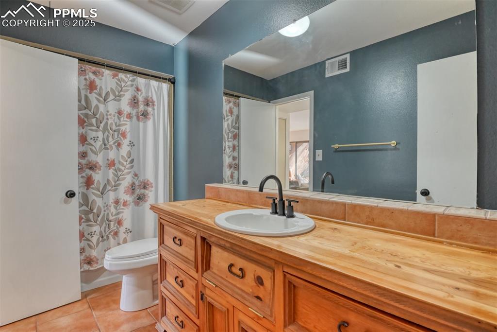 Full bath with a shower with curtain, light tile patterned floors, and vanity
