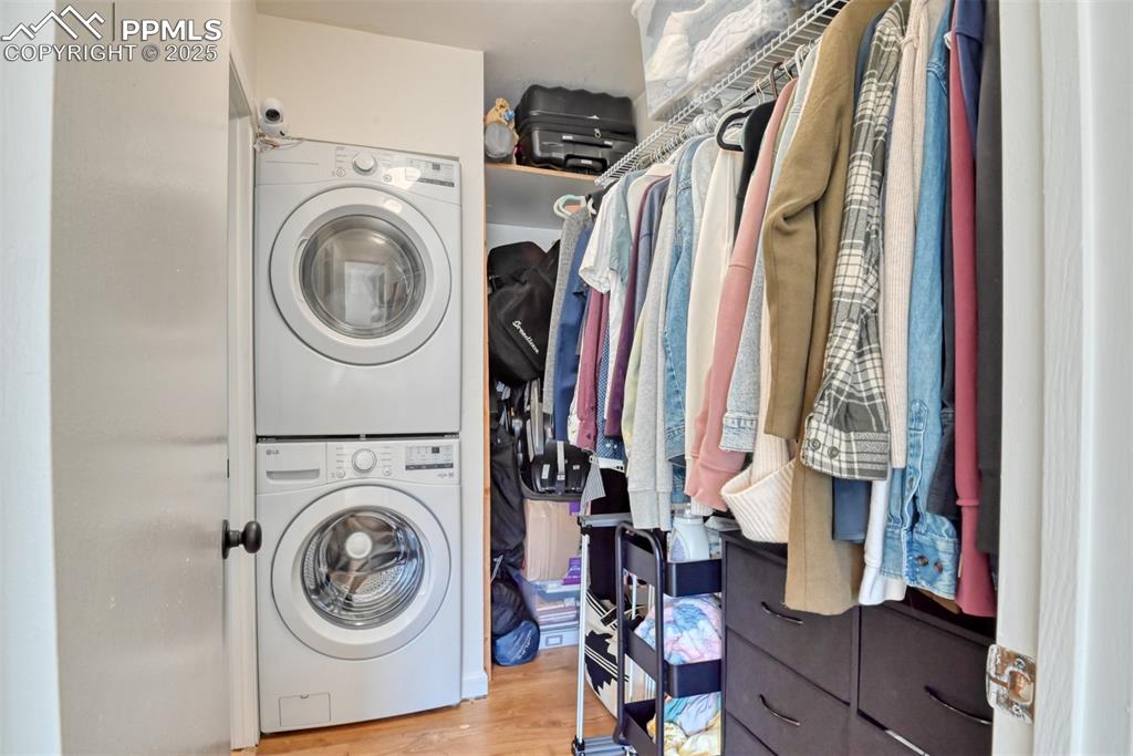 Laundry area featuring stacked washer and clothes dryer and light wood-style flooring