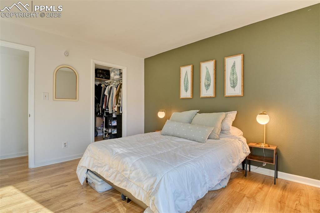 Bedroom with a walk in closet and light wood finished floors