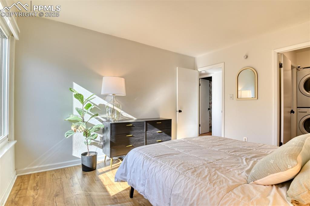 Bedroom featuring wood finished floors, estacked washer and dryer, and ensuite bath