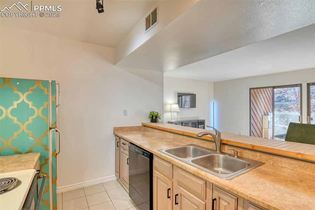 Kitchen featuring light countertops, electric stove, dishwashing machine, and light tile patterned flooring