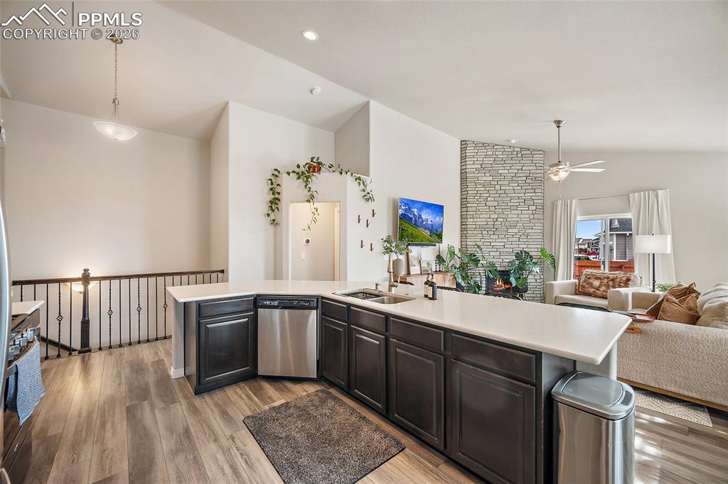 Kitchen featuring lofted ceiling, open floor plan, stainless steel appliances, light wood finished floors, and ceiling fan