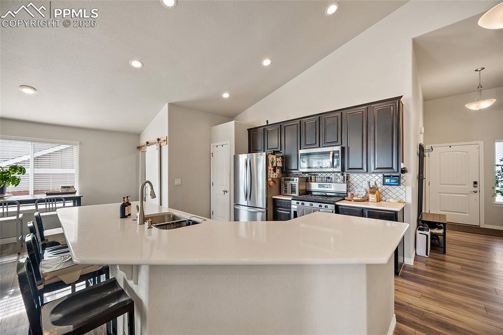 Kitchen with vaulted ceiling, stainless steel appliances, a spacious island, decorative backsplash, and recessed lighting