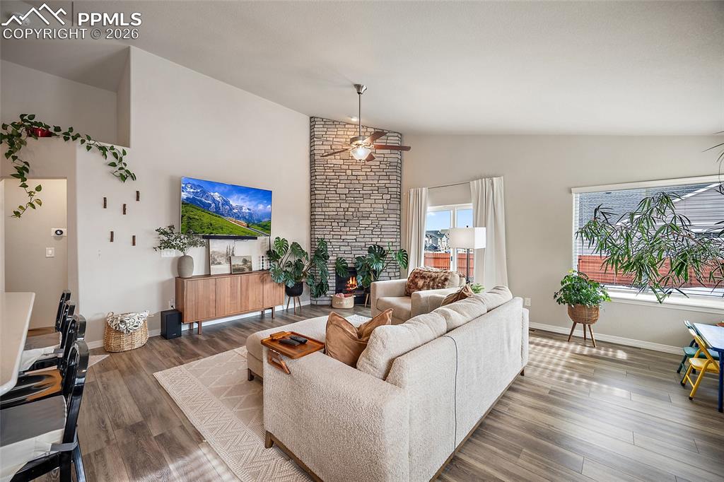 Living area with wood finished floors, high vaulted ceiling, and a fireplace