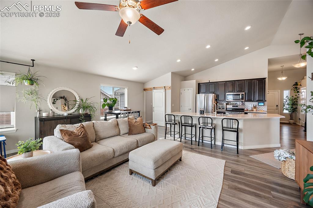 Living room featuring recessed lighting, light wood-type flooring, a ceiling fan, and high vaulted ceiling