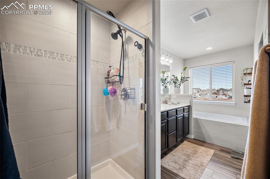 Bathroom featuring a garden tub, vanity, light wood-style floors, a shower stall, and recessed lighting