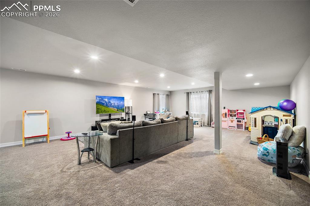 Living room with a textured ceiling, light colored carpet, and recessed lighting
