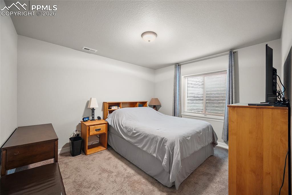 Carpeted bedroom featuring a textured ceiling and baseboards