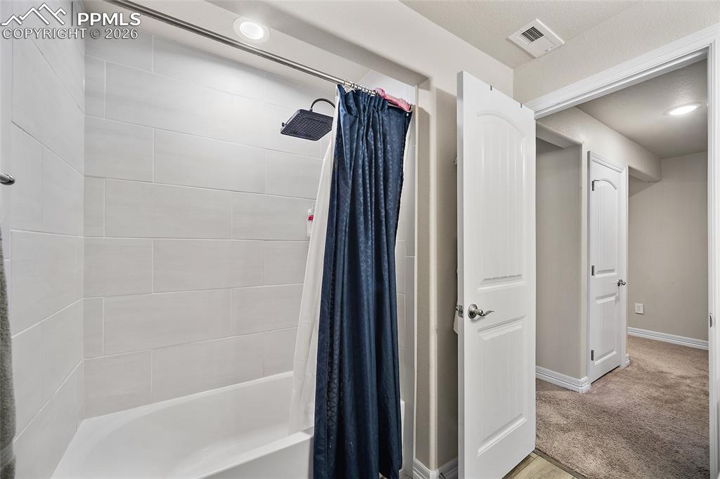Bathroom with shower / bath combo and light carpet