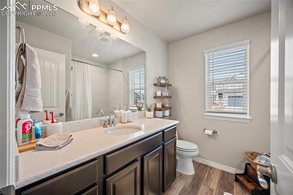 Bathroom with vanity, a shower with shower curtain, and dark wood-style flooring