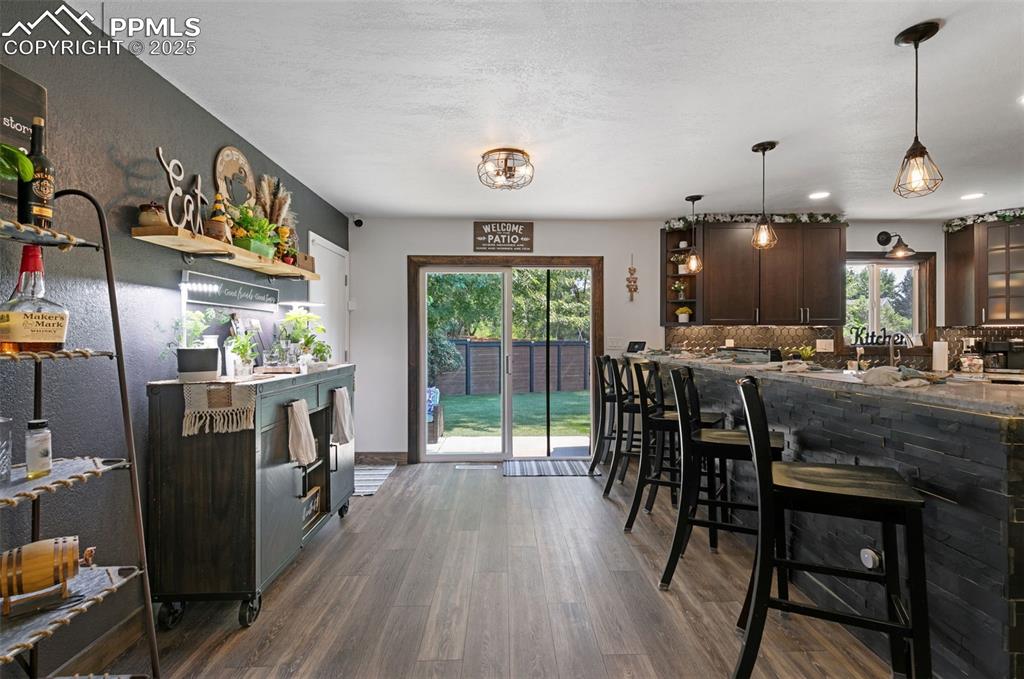 Kitchen featuring dark brown cabinets, dark wood finished floors, hanging light fixtures, a breakfast bar, and tasteful backsplash