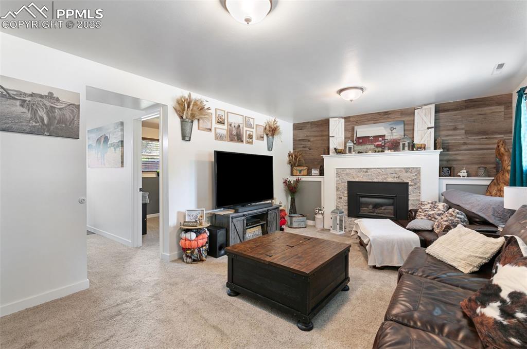 Living area featuring wooden walls, light carpet, and a fireplace