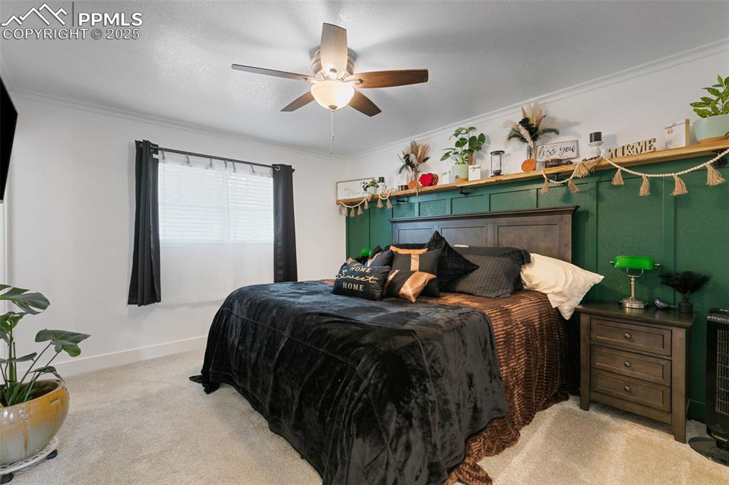 Bedroom featuring carpet floors, crown molding, ceiling fan, and a textured ceiling