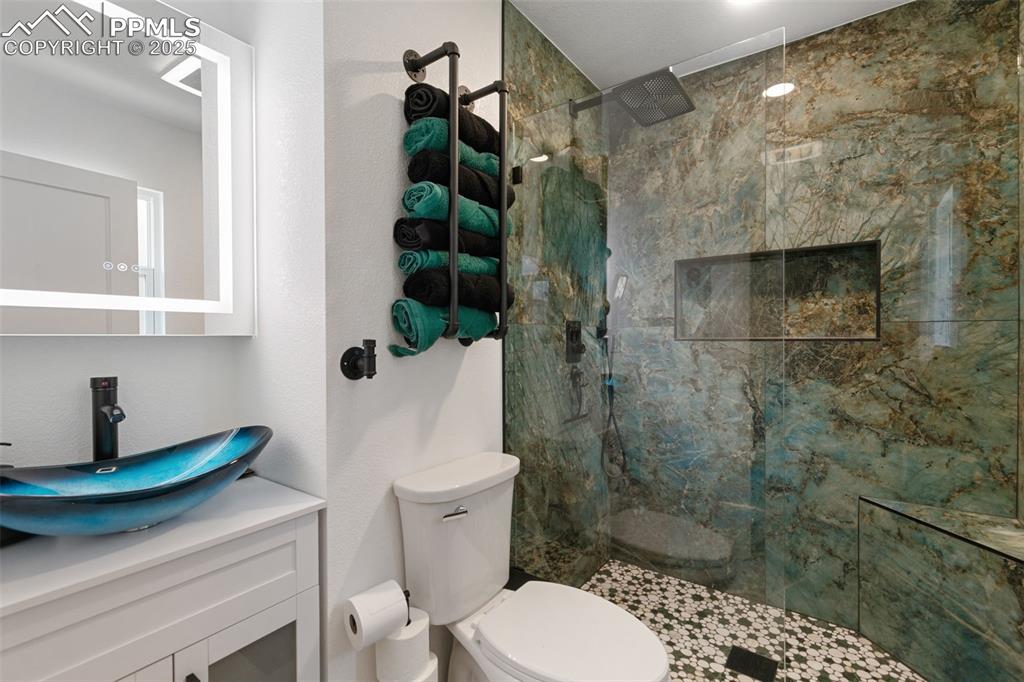 Bathroom featuring a marble finish shower and vanity