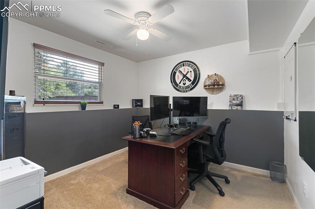 Home office with light colored carpet and ceiling fan