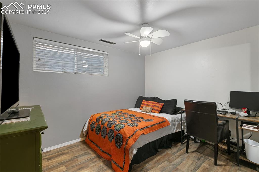 Bedroom with a desk, wood finished floors, and a ceiling fan