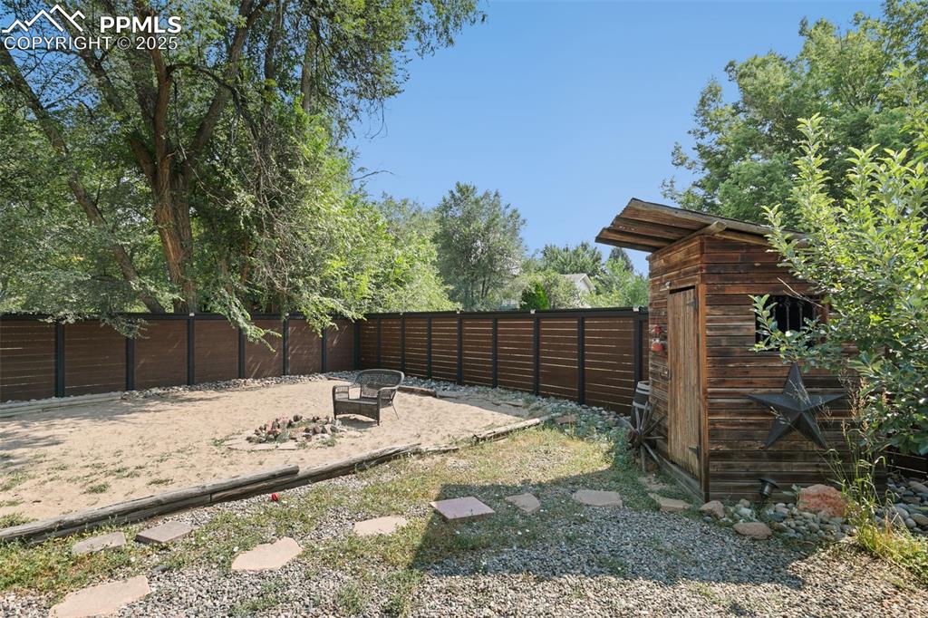 Fenced backyard featuring a patio area, a shed, and a fire pit