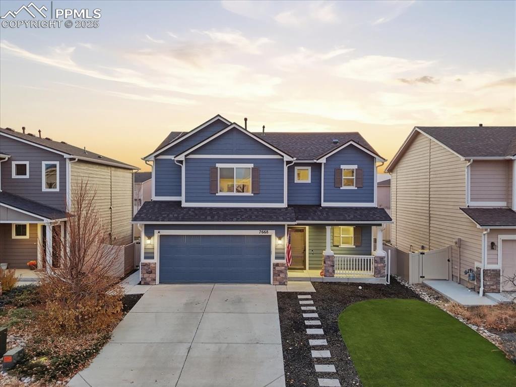 View of front of property with a porch, a shingled roof, stone siding, concrete driveway, and a garage