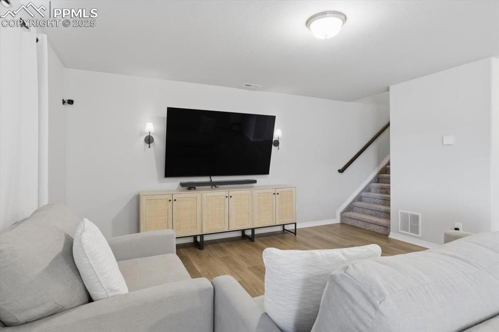 Living area with light wood-type flooring and stairs