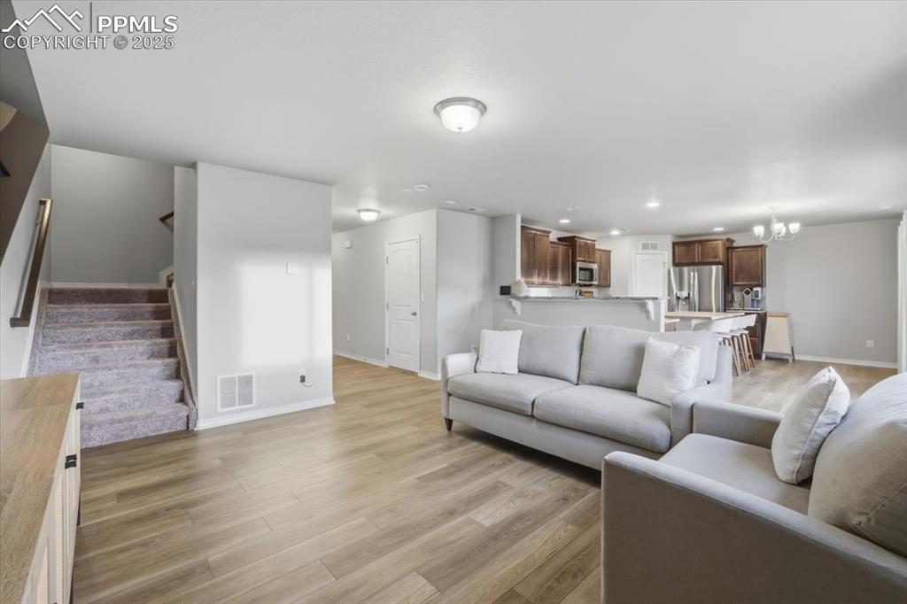 Living area with stairway, light wood finished floors, a chandelier, and recessed lighting